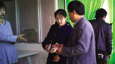 10月10日，青云店镇一斗狗场旁，赌客拿一沓百元钞向蓝衣女子投注。