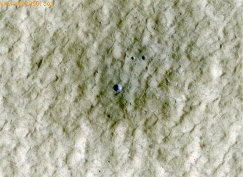 这张图片拍摄位置位于火星北半球中纬度地区，图像中间位置可见一个直径约6米的陨石坑，里面有亮色物质，在这张伪彩色图像中呈现蓝色。