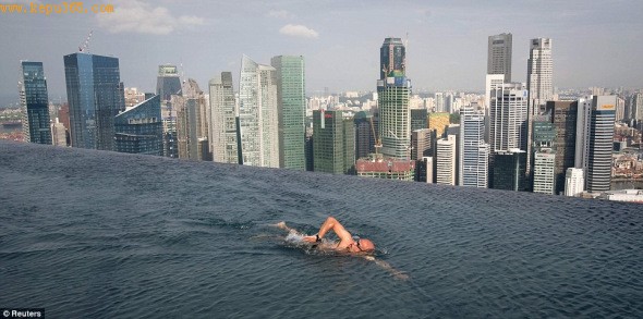 一位客人正在滨海湾金沙酒店55层高塔楼顶层“空中花园”泳池中游泳